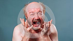Front view aged man hold hands in front of palms open fingers up looking up screaming furiously.
