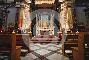 Front view of an altar in a large catholic church with wooden benches