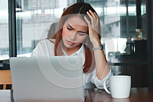 Front view of anxious upset young Asian business woman suffering from severe from depression in workplace.