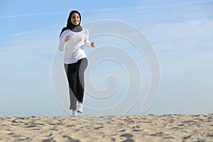 Front view of an arab saudi emirates woman running on the beach photo