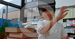 Front view of Asian schoolboy using virtual reality headset in classroom at school 4k