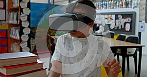 Front view of Asian schoolboy using virtual reality headset in classroom at school 4k
