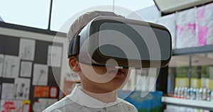 Front view of Asian schoolboy using virtual reality headset in classroom at school 4k