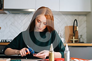 Front view of attractive young woman gluing envelopes on board with gifts for children making Christmas advent calendar