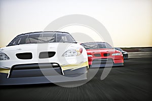 Front view of auto racing race cars racing on a track with motion blur.