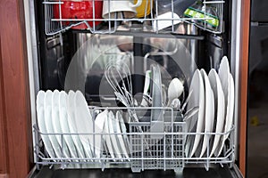 Front view at automatic dishwashing machine full loaded with utensils