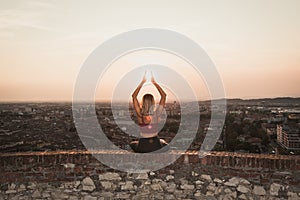 Front view of a back light of a faithful woman in yoga position holding the sun at sunset or sunrise