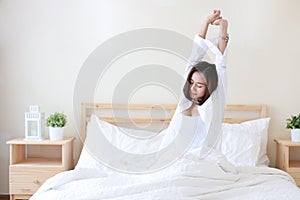 Front view beautiful and healthy young asian woman wake up in the morning, she stretching after wake up in the morning on white be