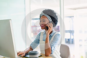 Female graphic designer talking on mobile phone at desk