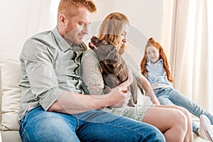 Front view of beautiful redhead family playing with puppy at home