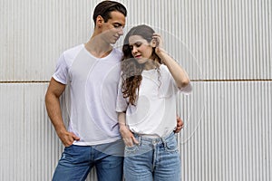 Front view of beautiful young couple hugging, looking at camera and smiling while standing outdoors