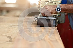 Front view of belt sander working on a piece wood with hands of worker with copy space. Selective focus and shallow depth of field