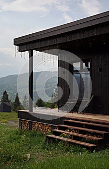 Front view of black modern cabin with terrace on Carpathian mountains in Ukraine