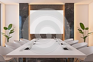 Front view on blank white poster on brick wall in stylish meeting room with white conference table with modern laptops surrounded