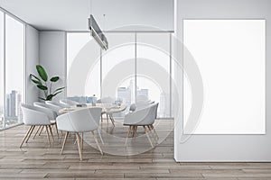 Front view on blank white poster on light grey wall in stylish sunlit meeting room with modern light furniture and city view
