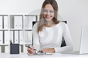 Front view of blond woman writing in clipboard