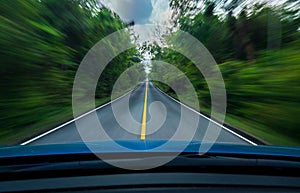 Front view of blue car driving with fast speed on the middle of asphalt road with white and yellow line of traffic symbol