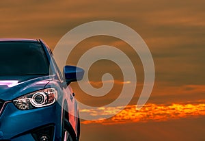 Front view of blue compact SUV car with sport and modern design parked on concrete road at sunset with beautiful orange sky.