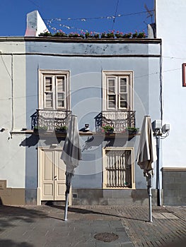 Front view of blue facade with white closed windows and door under clear blue sky. A blue house in a Tenerife town showing sash photo