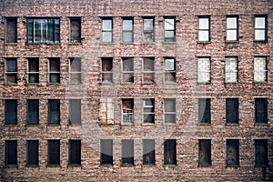 Front view of a boarded-up abandoned brick skyscraper building windows from the street in New York City