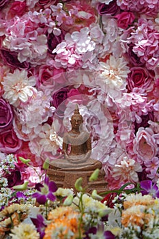 front view brown buddha in front of various flowers, cascading flowers and roses colorful background, worship, banner, template,