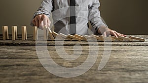 Front view of a businessman stopping domino effect with his finger