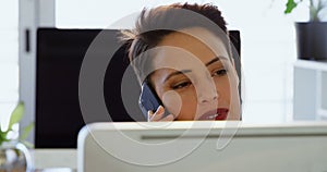 Front view of Caucasian Businesswoman talking on mobile phone at desk in a modern office 4k