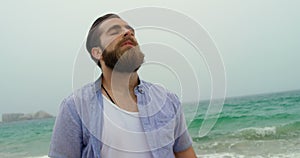 Front view of Caucasian man standing with eye closed on the beach 4k