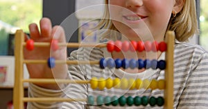Front view of Caucasian schoolgirl learning mathematics with abacus in the classroom 4k