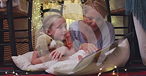 Front view of caucasian woman reading a story to her daughter at home