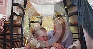 Front view of caucasian woman reading a story to her daughter at home