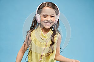 Front view of cheerful girl listening music in headphones