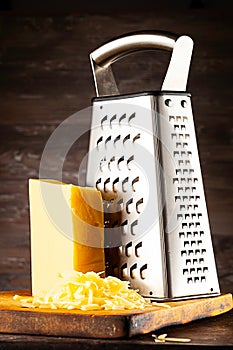 front view on cheese and grater lying on old burned cutting board.