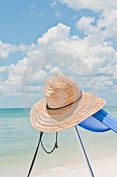 Straw hat with wide brim and blue scarf, at a tropical shoreline photo