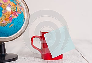 Front view close up globe map world earth coffee cup sticky note lying retro vintage rustic old table background