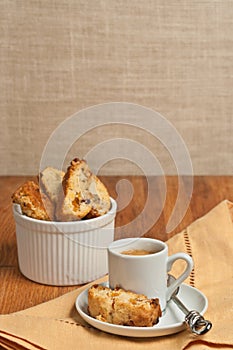 Front view, close up of homemade, freshly baked, apricot walnut biscotti and cup of espresso on a round, small, white saucer with