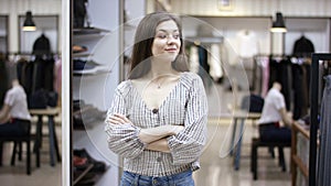 A front view close up shot of a young beautiful woman standing in a clothing boutique looking straight into camera and