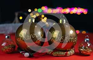 Front view and close-up of some beautiful golden handmade Christmas balls, where you can read Merry Christmas. In the background