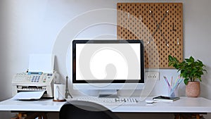 Front view computer with empty display, houseplant and stationery on white table. Home office desk