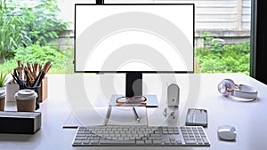 Computer with empty display and office supplies on white table.