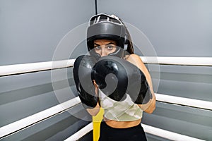 Woman with protective gloves and headgear in attack position on a ring boxing