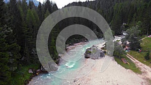 Front view. A couple are sitting on a large stone, a boulder, among the incredibly beautiful river of turquoise color, Dolomites m