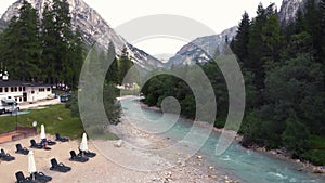 Front view. A couple are sitting on a large stone, a boulder, among the incredibly beautiful river of turquoise color, Dolomites m