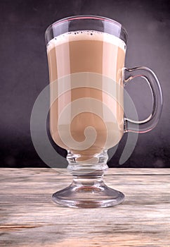 Front view of a cup of aromatic coffee standing on wooden textured background