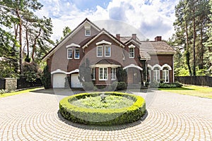 Front view of a driveway with a round garden and big, english st