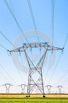 Front view of an electricity pylon in the countryside under a clear blue sky