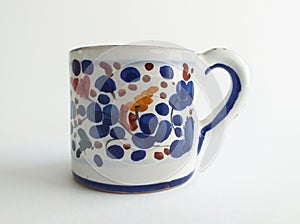 Front view of elegant painted ceramic mug with blue and grenade decorative elements on white background