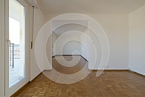 Front view of an empty room with windows for natural light. Parquet floor