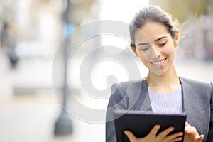 Front view of an executive using tablet in the street