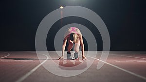 Front view of a female athlete starting her sprint on a running track. Runner taking off from the starting blocks on